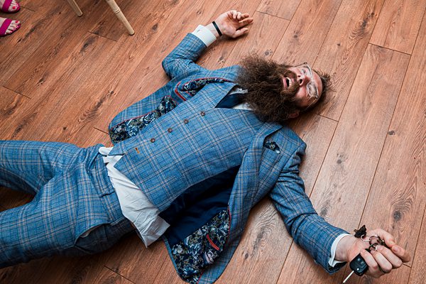 Man in blue suit lying on wooden floor.