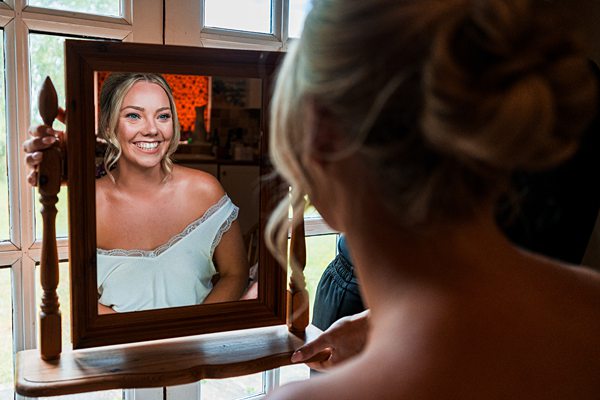 Woman smiling at herself in mirror.