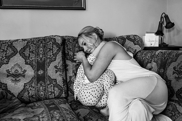 Woman embracing child on patterned couch, monochrome photo.