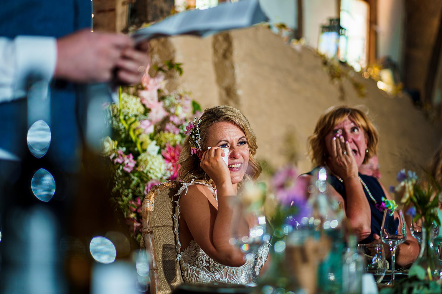 Emotional wedding guests wiping tears at reception.