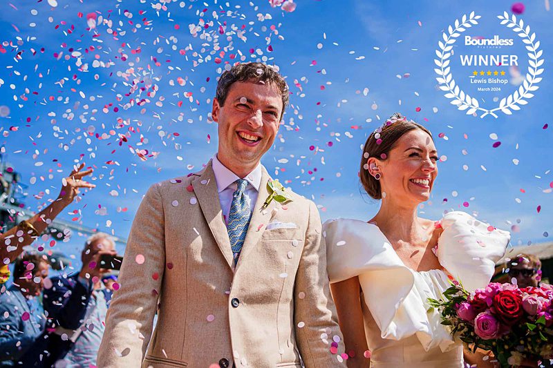 Joyful wedding couple with confetti and blue sky.