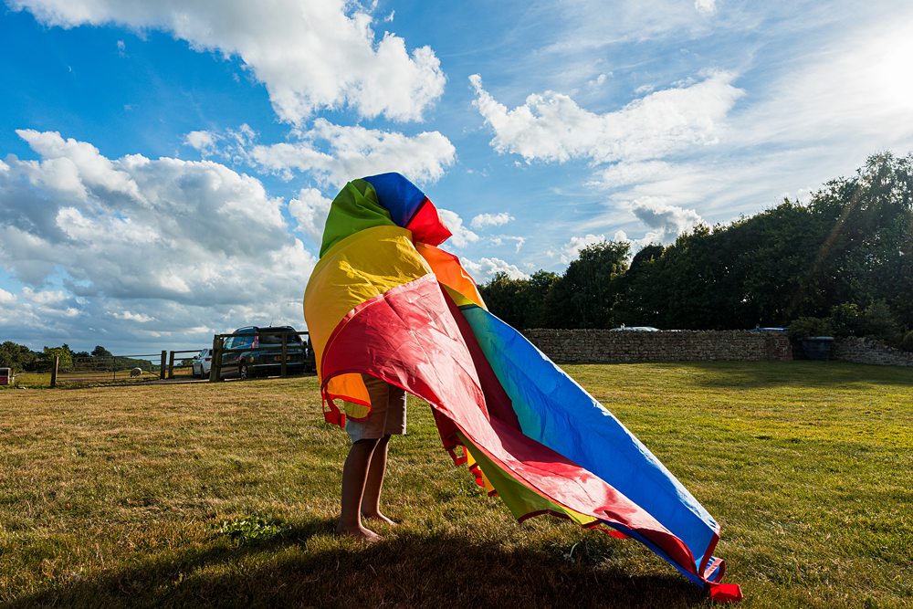 Child playing with colourful kite in sunny field.
