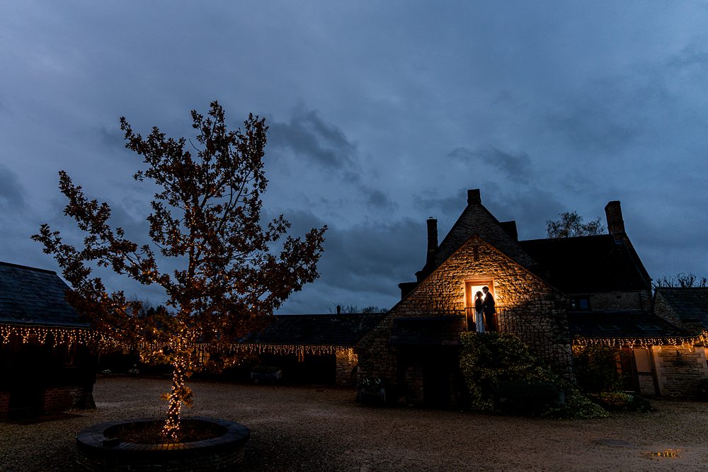 Silhouetted couple in doorway, fairy lights on tree.