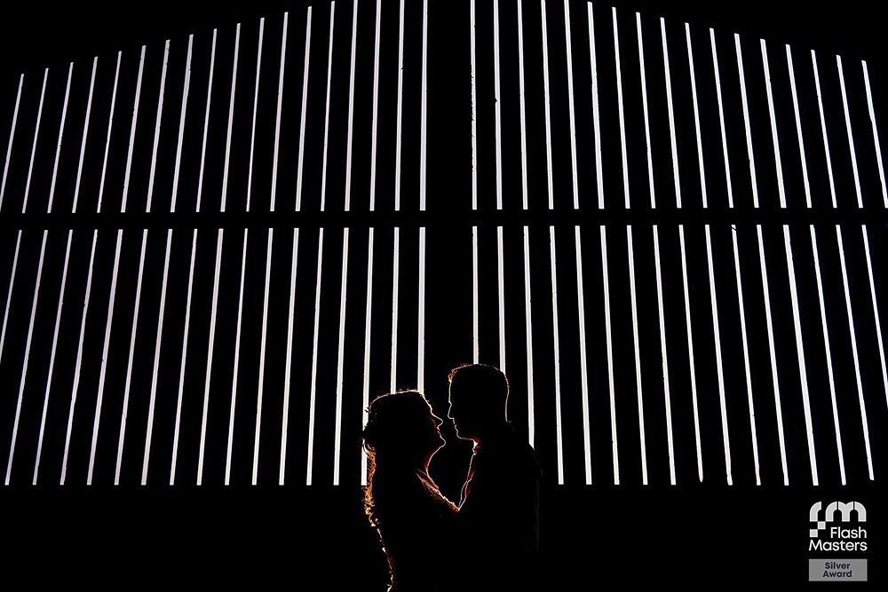 Silhouette of couple against striped lights in darkness.