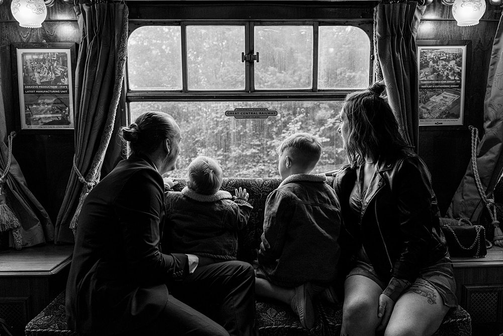 Family looking out train window together.
