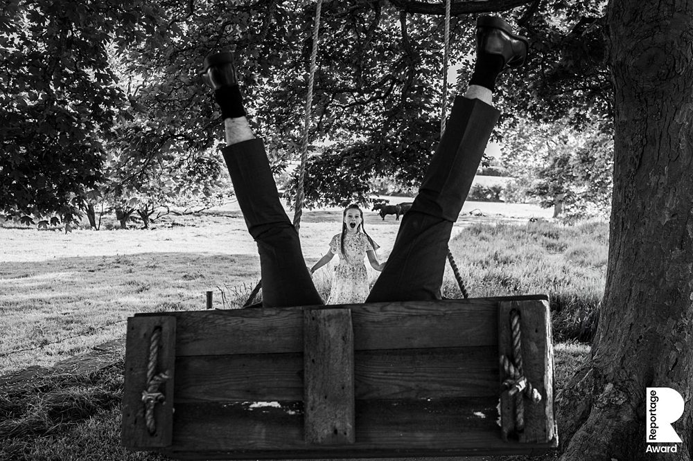 Person upside down on swing, surprised child watching.