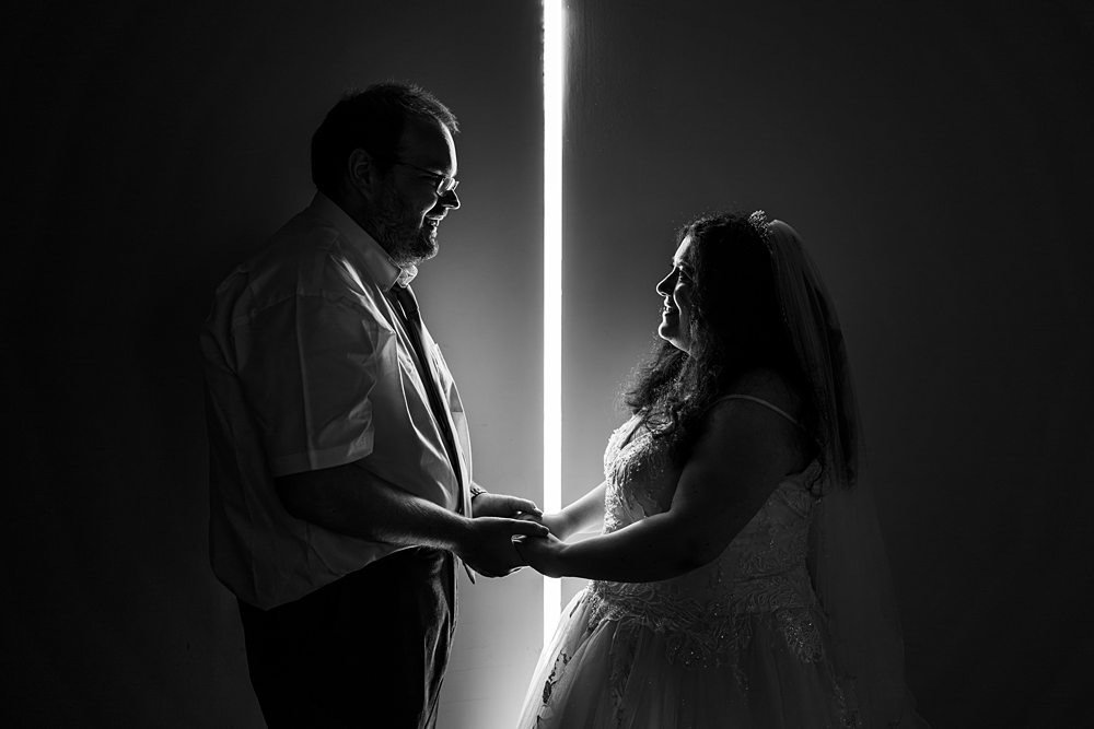 Silhouetted couple holding hands at wedding ceremony.