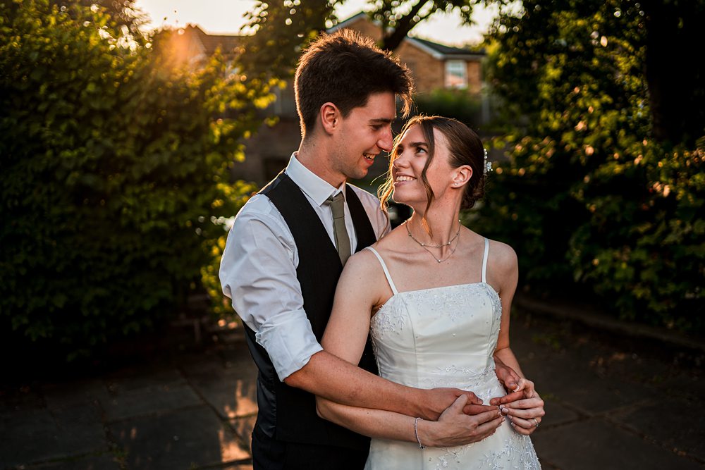 Couple embracing outdoors in wedding attire.