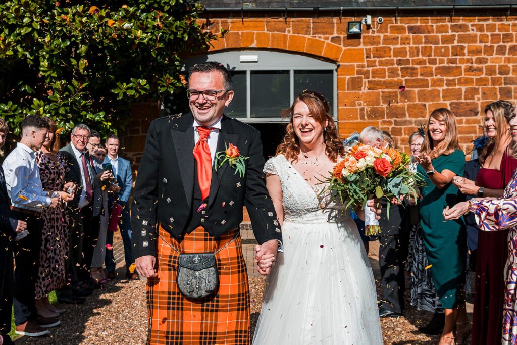 Couple celebrating wedding with guests and confetti.
