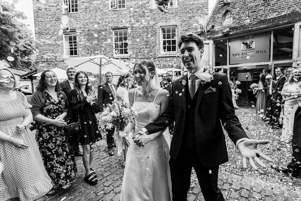 Wedding couple with guests and confetti outside venue.