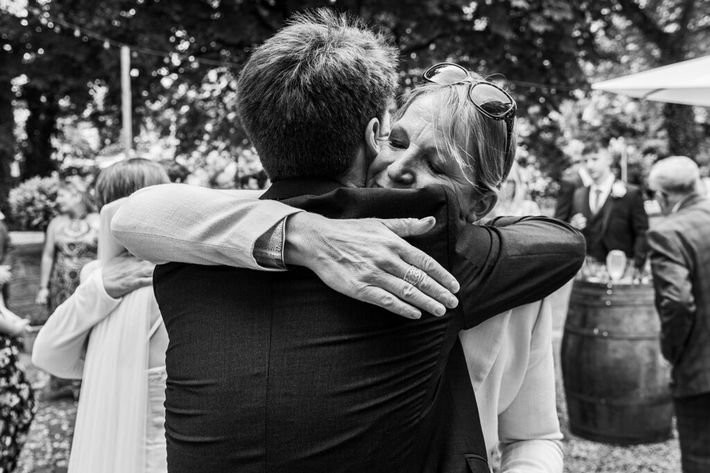 People hugging at outdoor event, black and white photo.