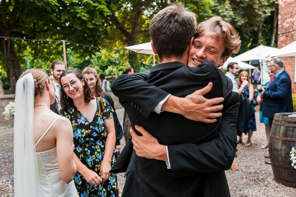 Wedding guests celebrating outdoors with hugs and smiles.