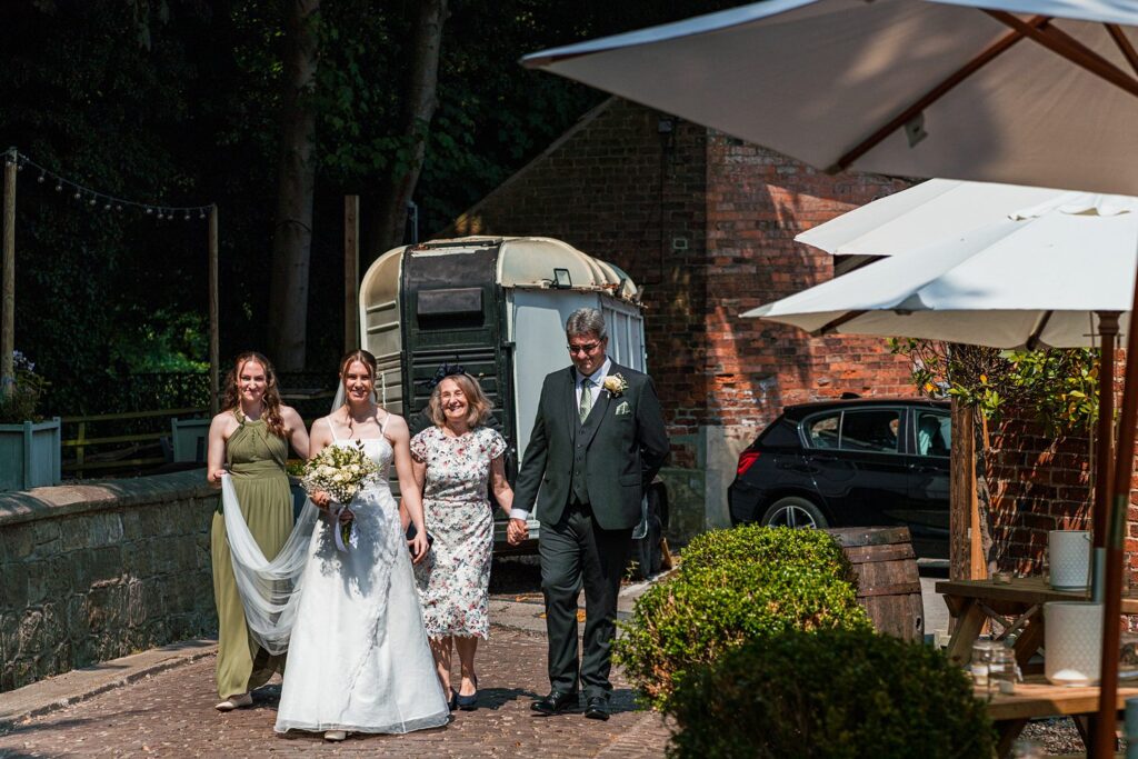 Wedding party walking outside, bride holding bouquet.