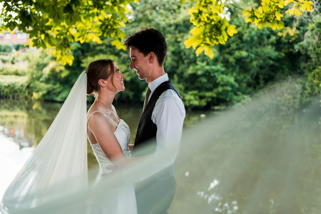 Smiling bride and groom outdoors in lush greenery.