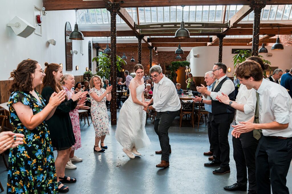 Wedding guests dancing and clapping in celebration.