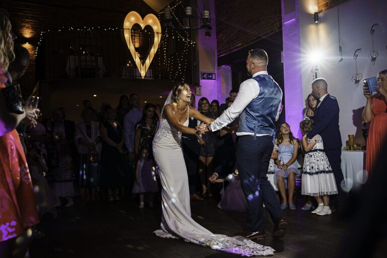Couple dancing at wedding reception with heart decoration.