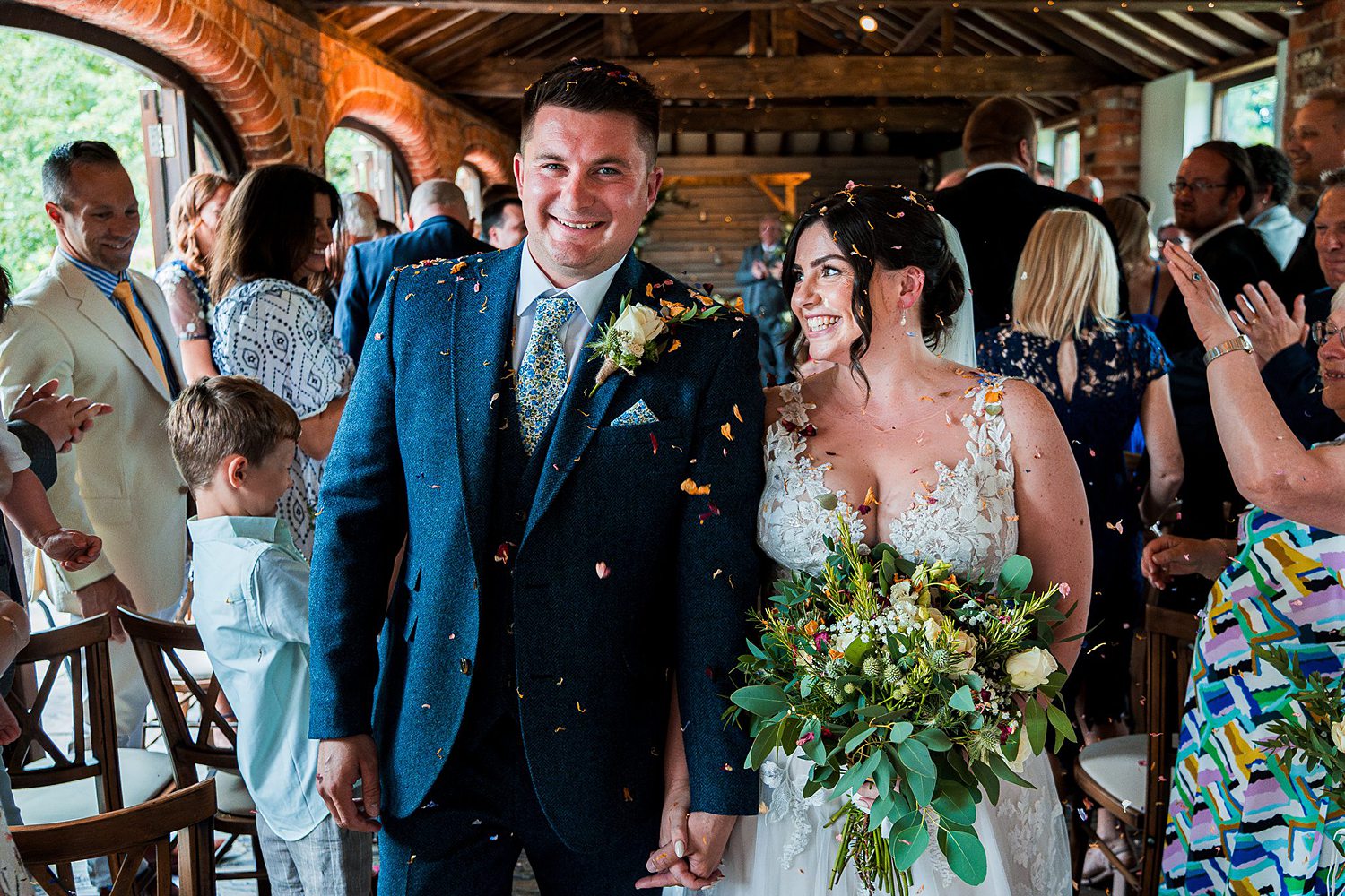 Smiling newlyweds walking through confetti celebration.