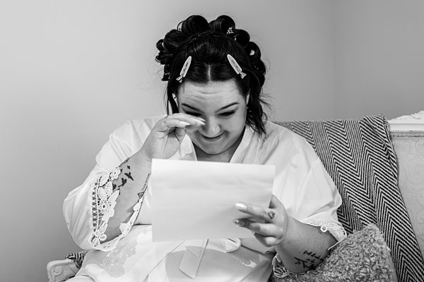 Woman reads letter, wipes tears in emotional moment.