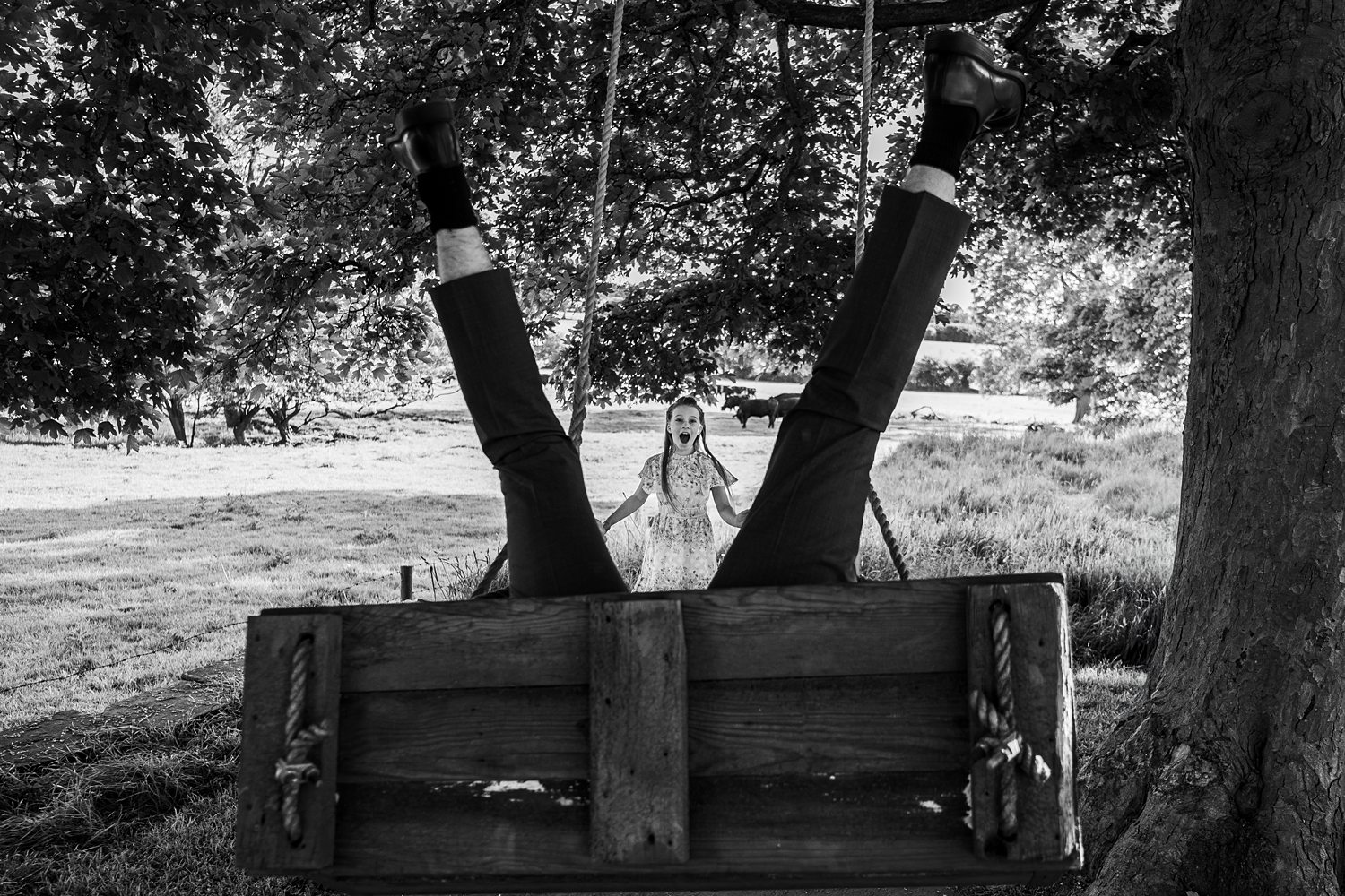 Man upside down on swing, surprised woman watching.