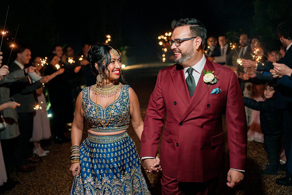 Couple at wedding with sparklers at night.