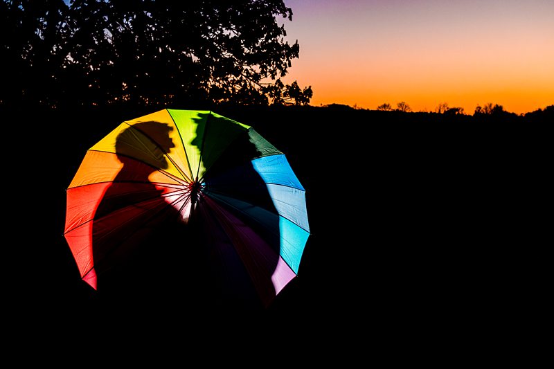 Colourful umbrella silhouette against sunset sky.