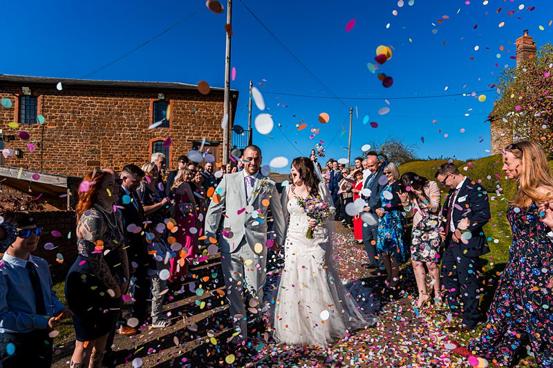 Bride and groom walking through confetti celebration.