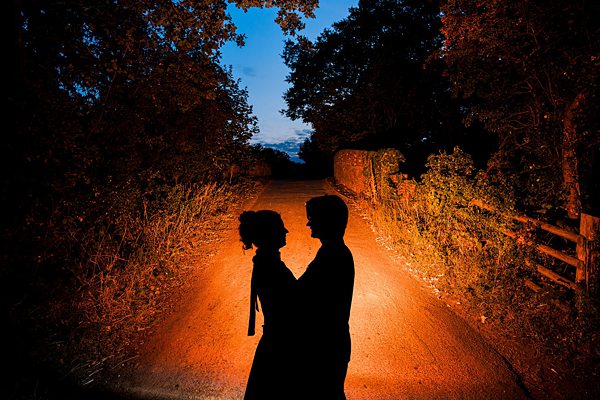 Couple silhouetted on a rural road at sunset.