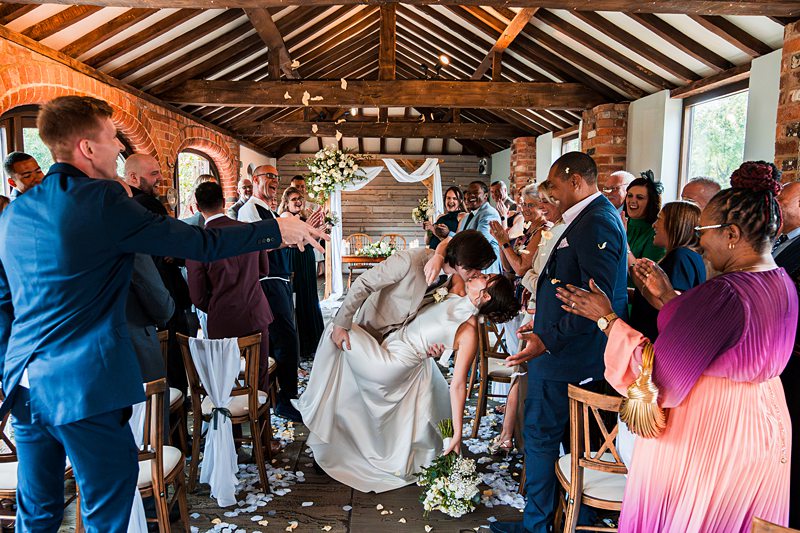 Newlyweds kissing at indoor wedding ceremony.
