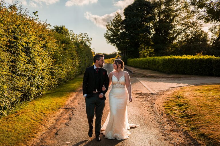 Bride and groom walking down a country lane.