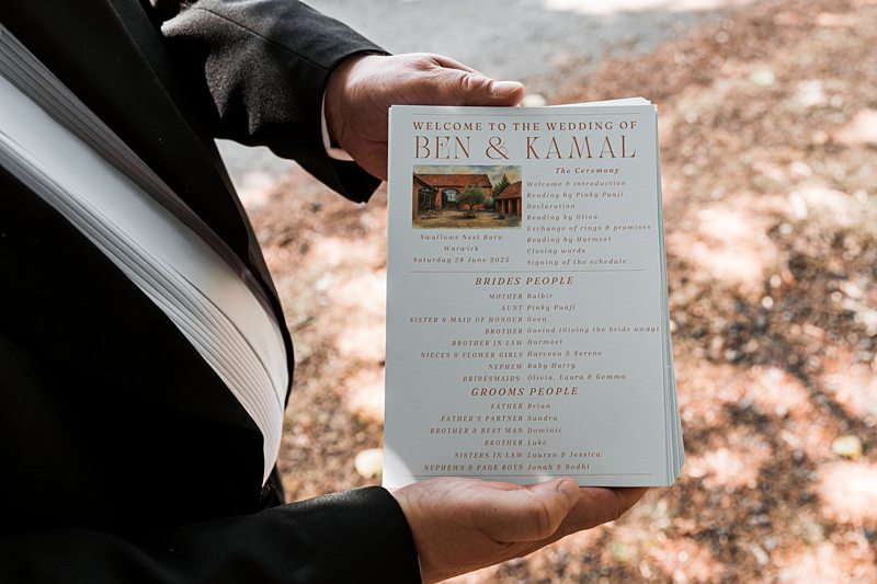 Wedding invitation held by person in black suit.