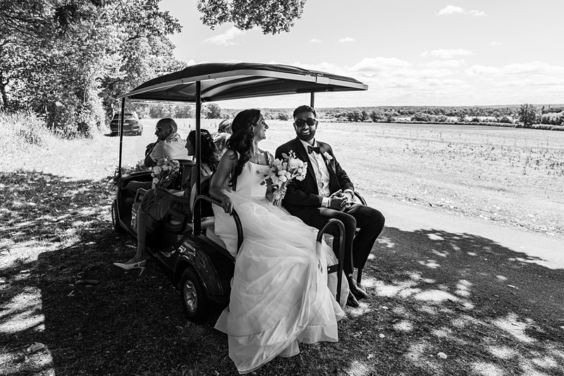 Bride and groom in golf cart, countryside wedding