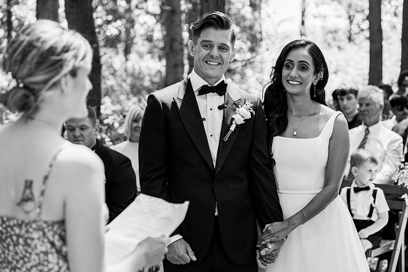 Wedding ceremony in forest setting with guests watching.