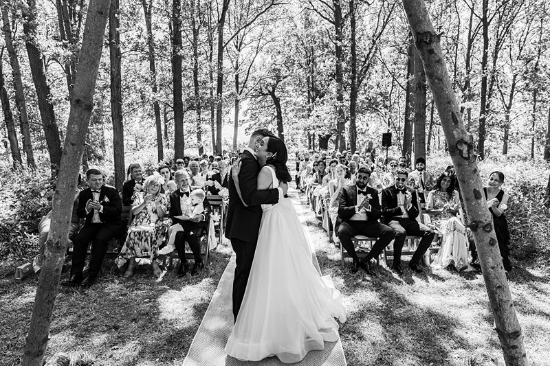 Bride and groom kiss at outdoor wedding ceremony.