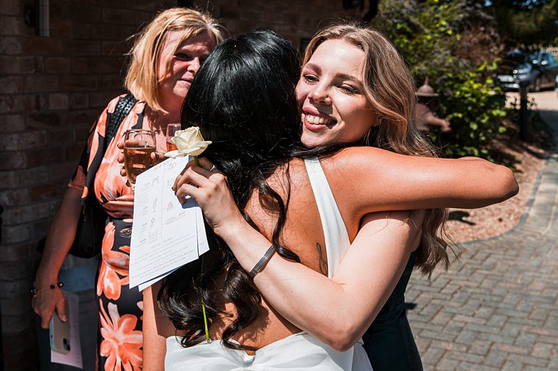 People hugging at outdoor gathering, sunny day.
