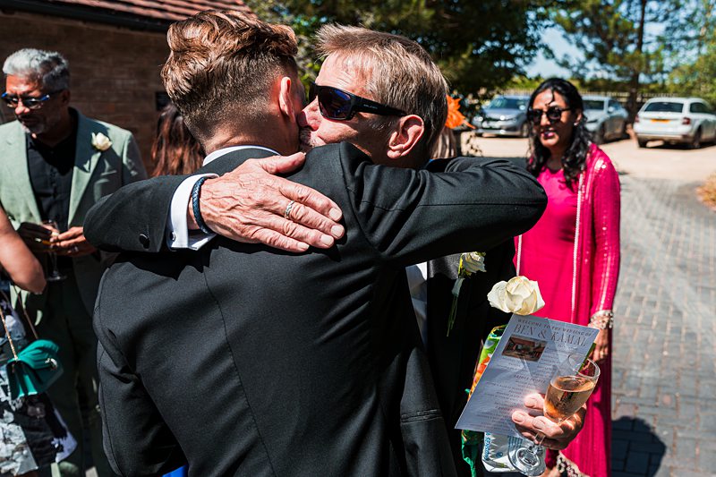 Guests hugging at outdoor celebration with drinks.