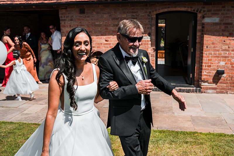 Bride walking down the aisle with elder gentleman.
