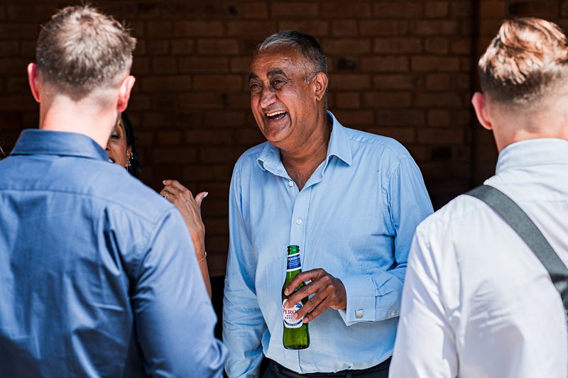 Man laughing, holding beer bottle at event