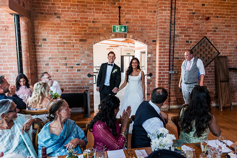 Wedding couple enters reception to applause.