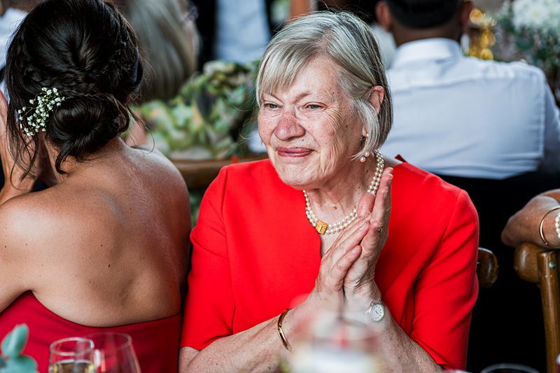 Smiling older woman clapping at event.
