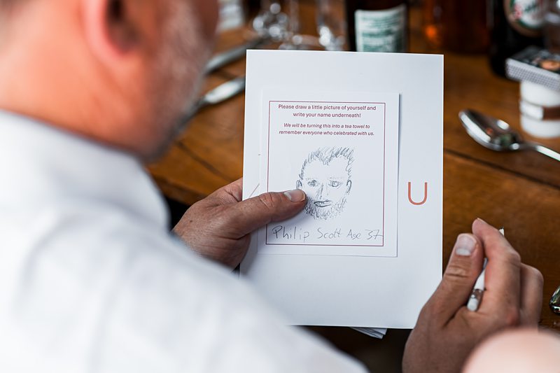 Man sketching on a card at a table.