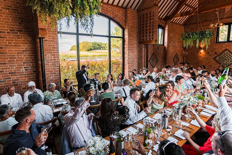 Wedding reception toast in rustic venue.