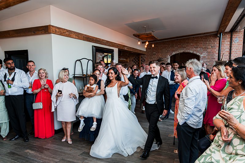 Wedding couple entering reception with guests applauding.