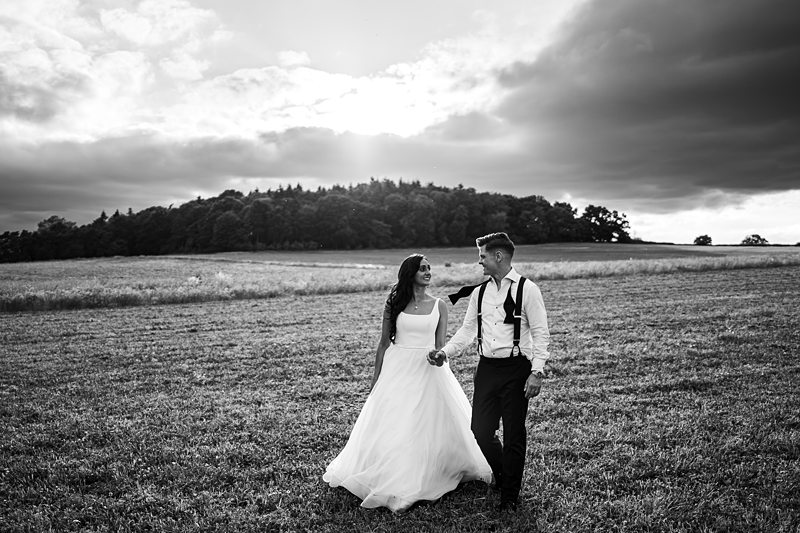 Couple walking in field during overcast sunset.
