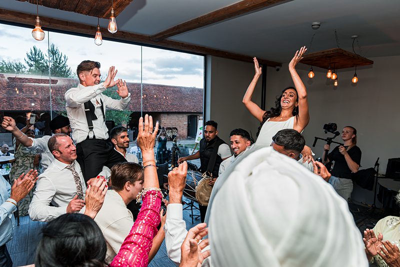 Wedding guests dancing and celebrating indoors.