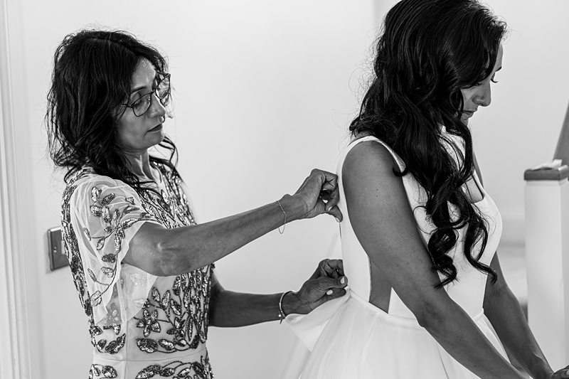 Woman fastening bride's wedding dress