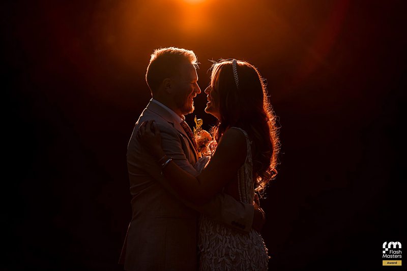 Couple embracing at sunset for wedding photograph.