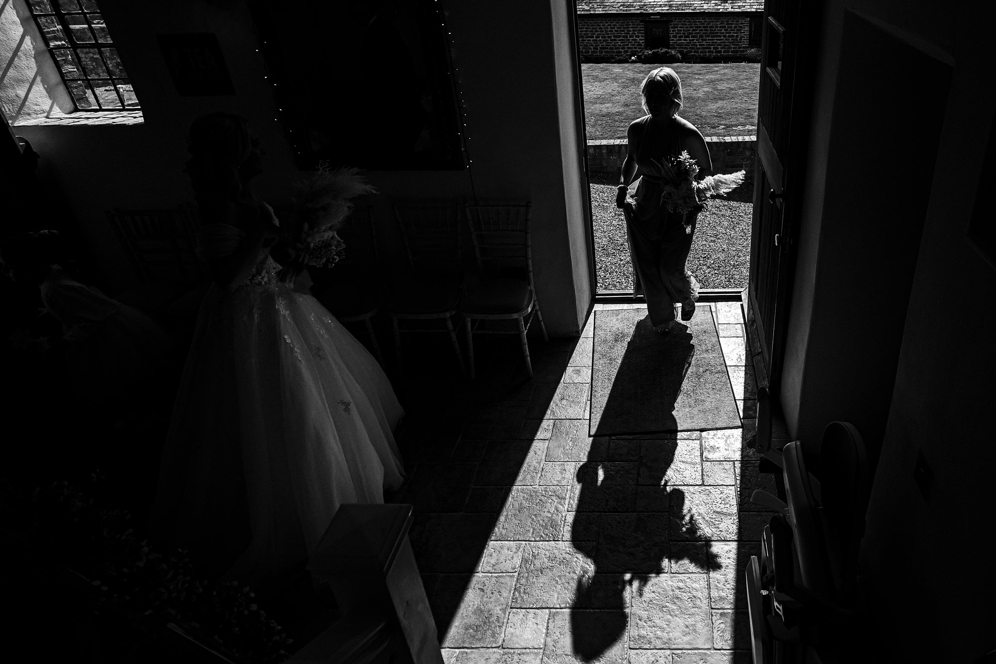 Silhouetted woman and bride in doorway with shadows.
