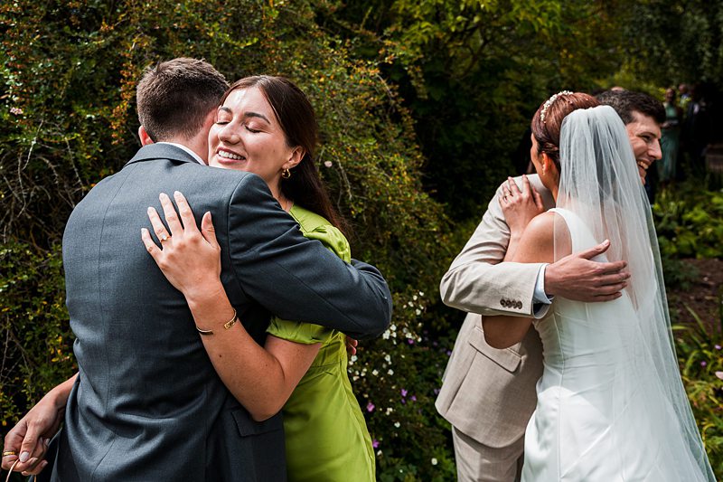 Couples hugging at outdoor wedding ceremony.