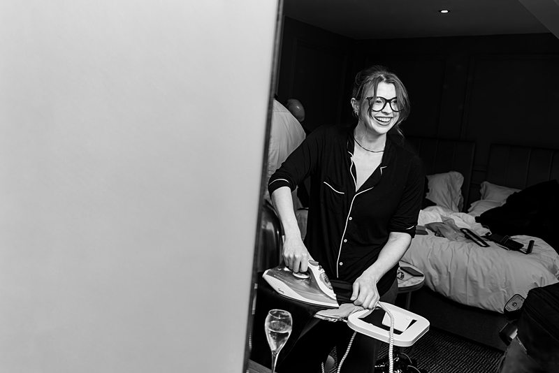 Woman smiling while ironing in pyjamas.