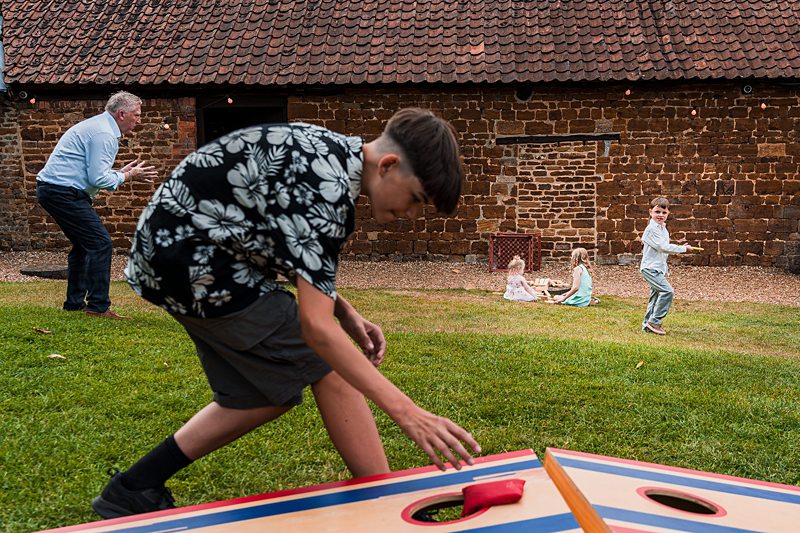 Children playing corn hole game outdoors.